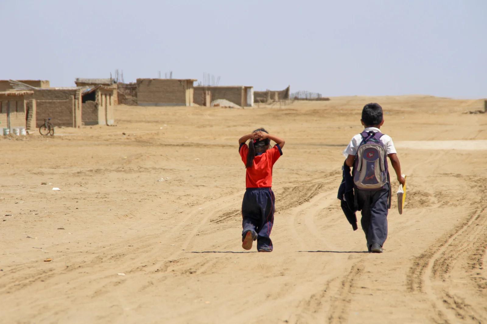 Two children walking in sandy area