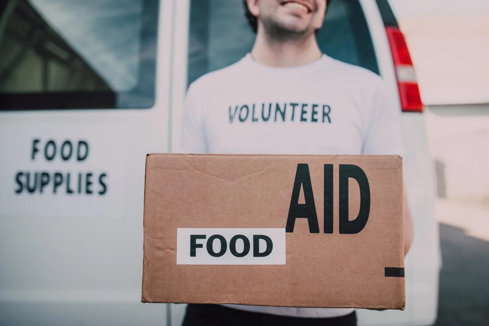 Volunteer man holding a food aid box